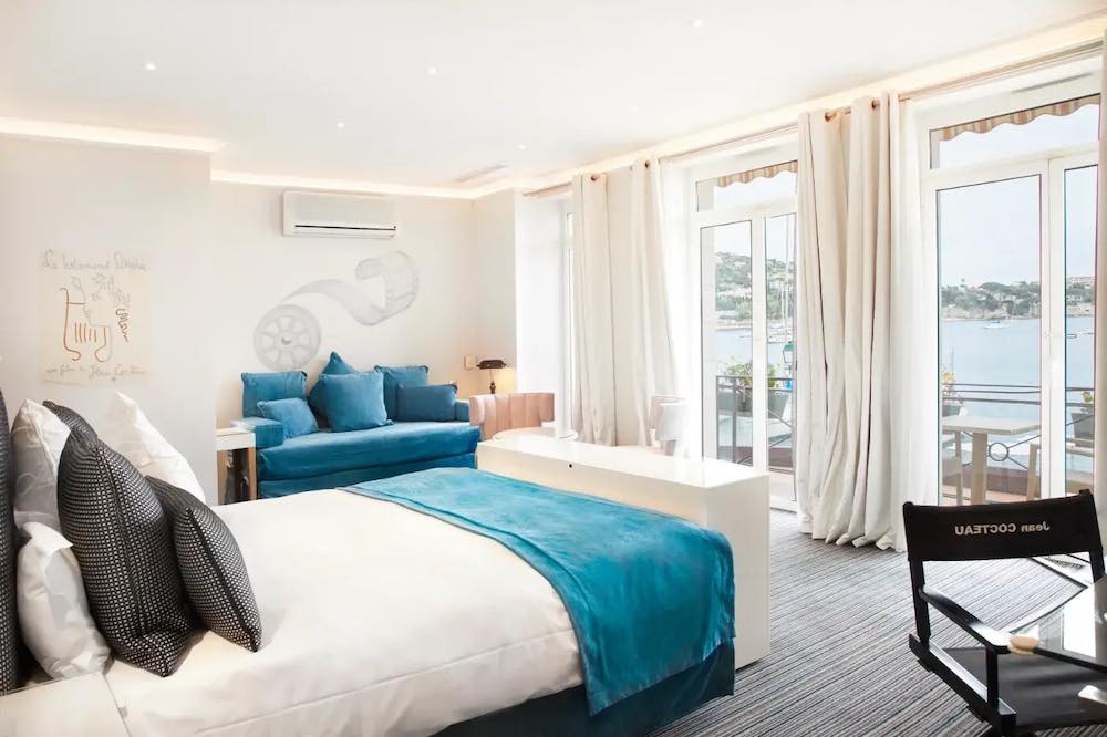 Bright bedroom with petrol-colored bedding and sofa