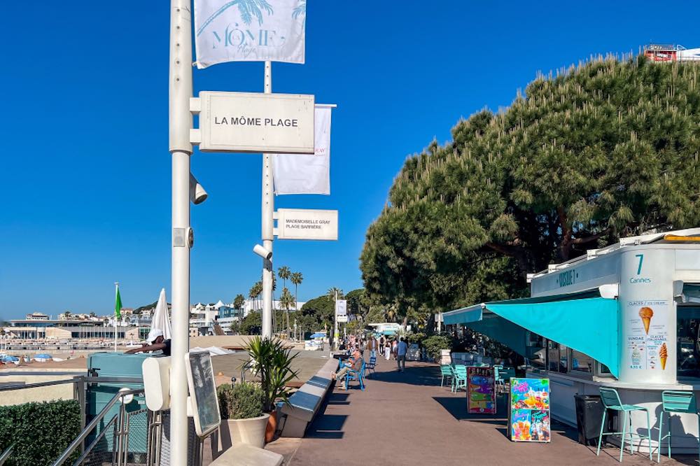 Croisette in Cannes at La Mome Plage with a kiosk and people sitting in blue chairs