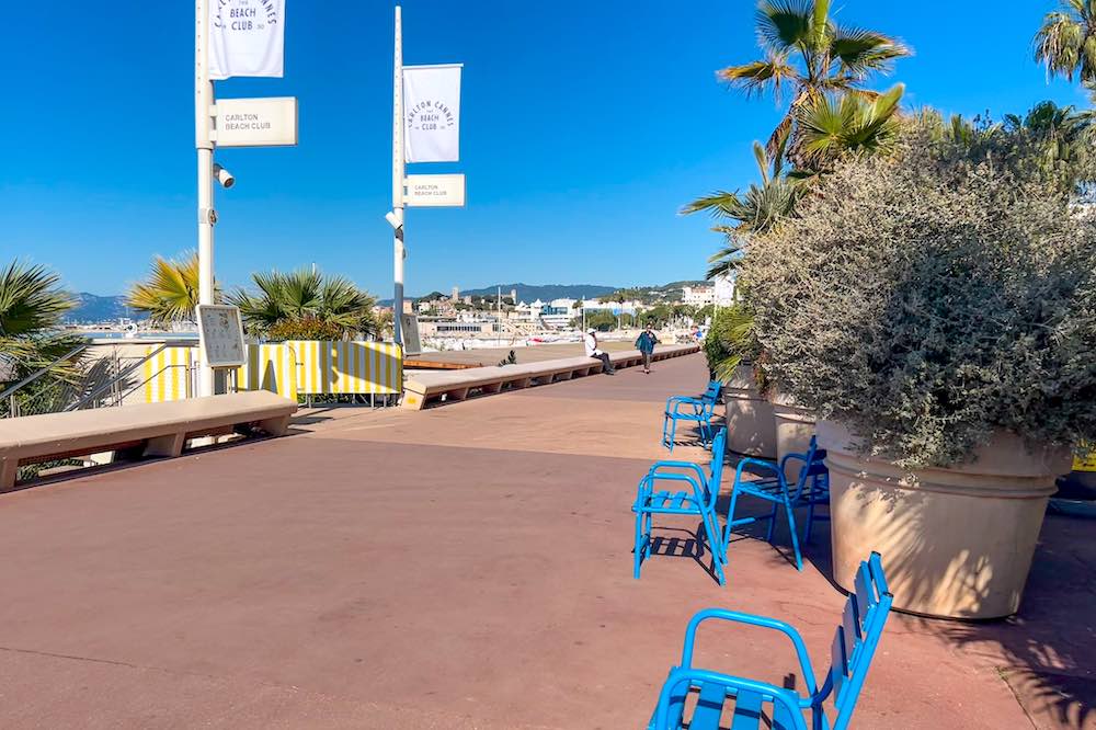 Blue chairs along La Croisette in Cannes in front of the entrance to the Carlton Cannes Beach Club