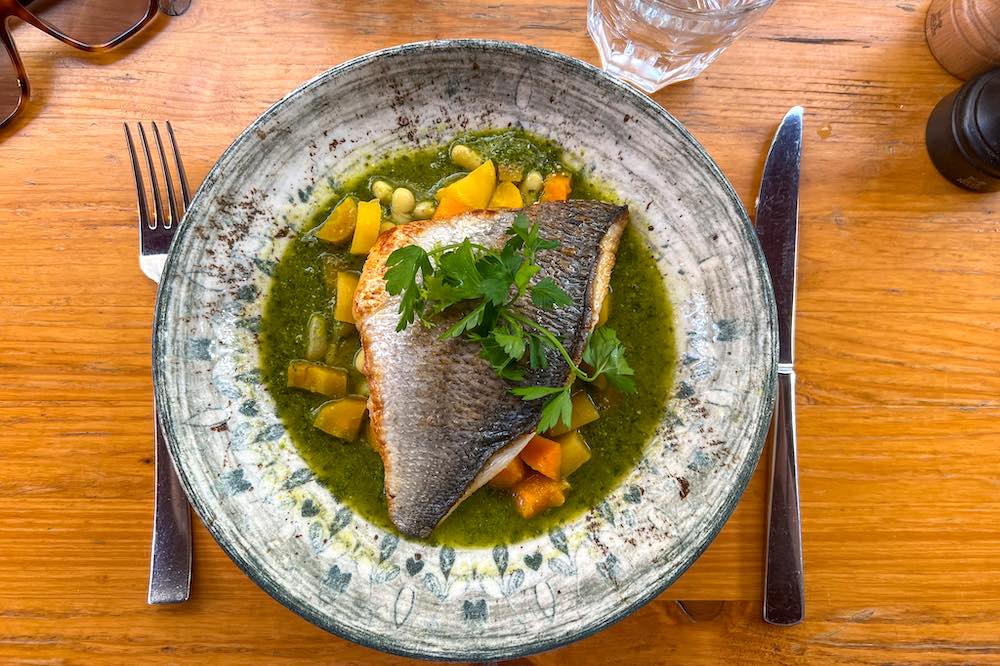 Sea bream fillet in a pesto soup with vegetables and pine nuts at La Cantine Provencale restauraunt in Cannes